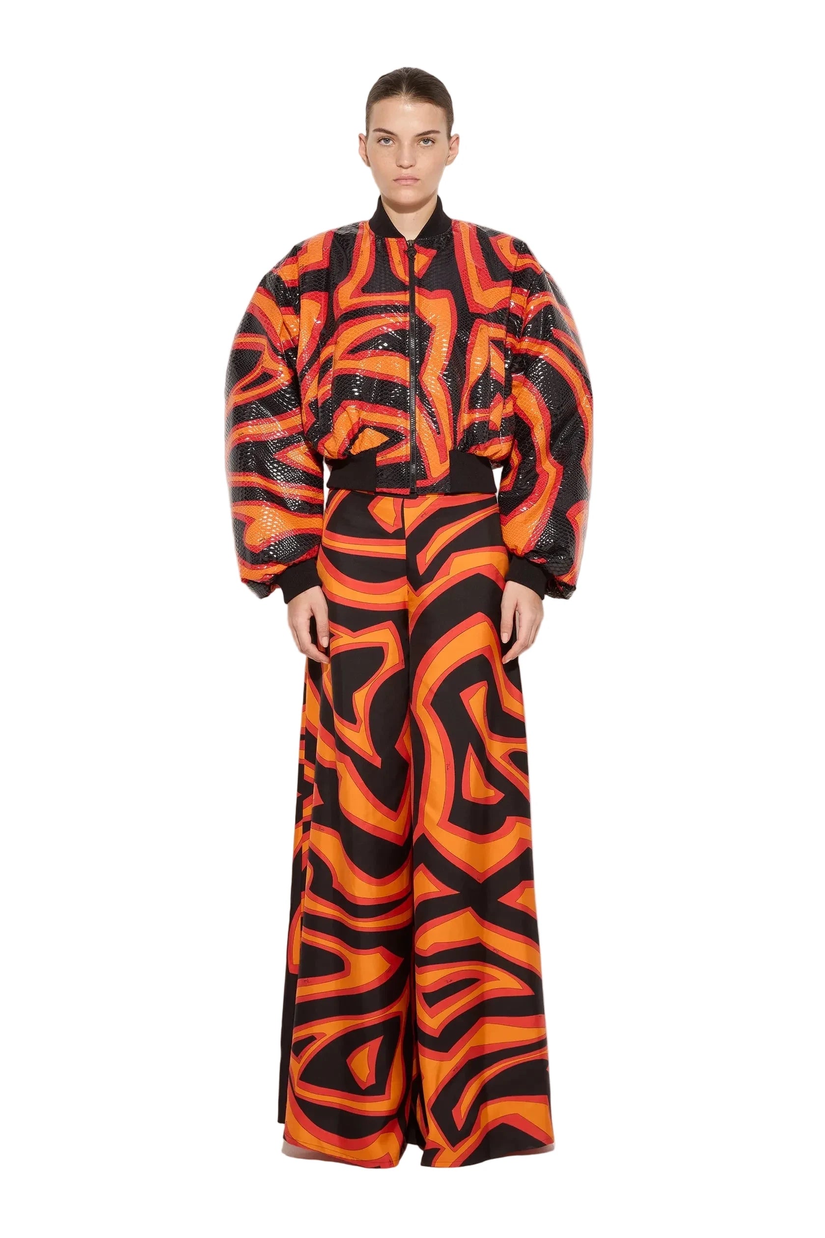 Person wearing a vibrant orange and black patterned outfit on a white background