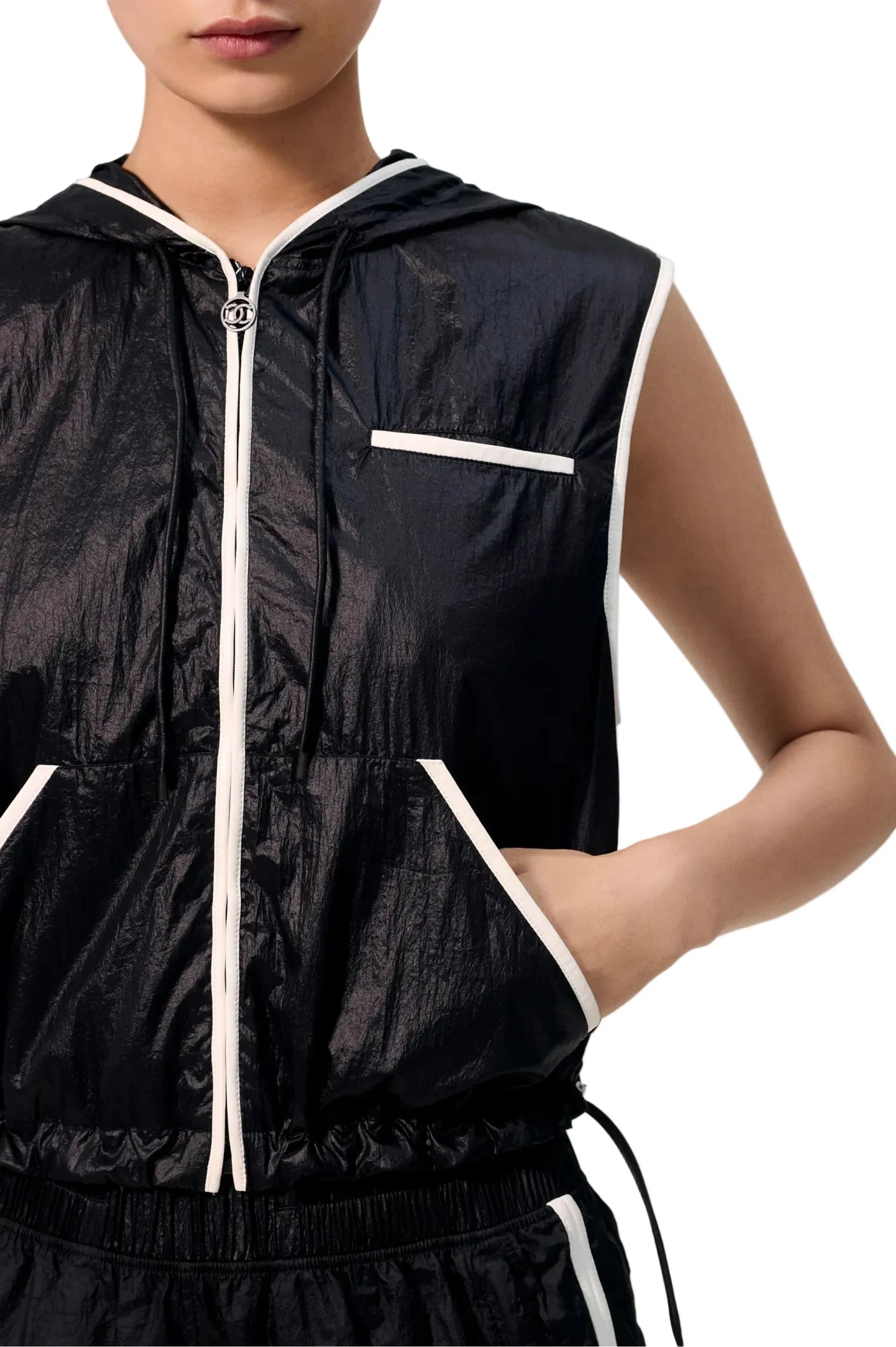Black sleeveless jacket with white zipper and trim on a neutral background