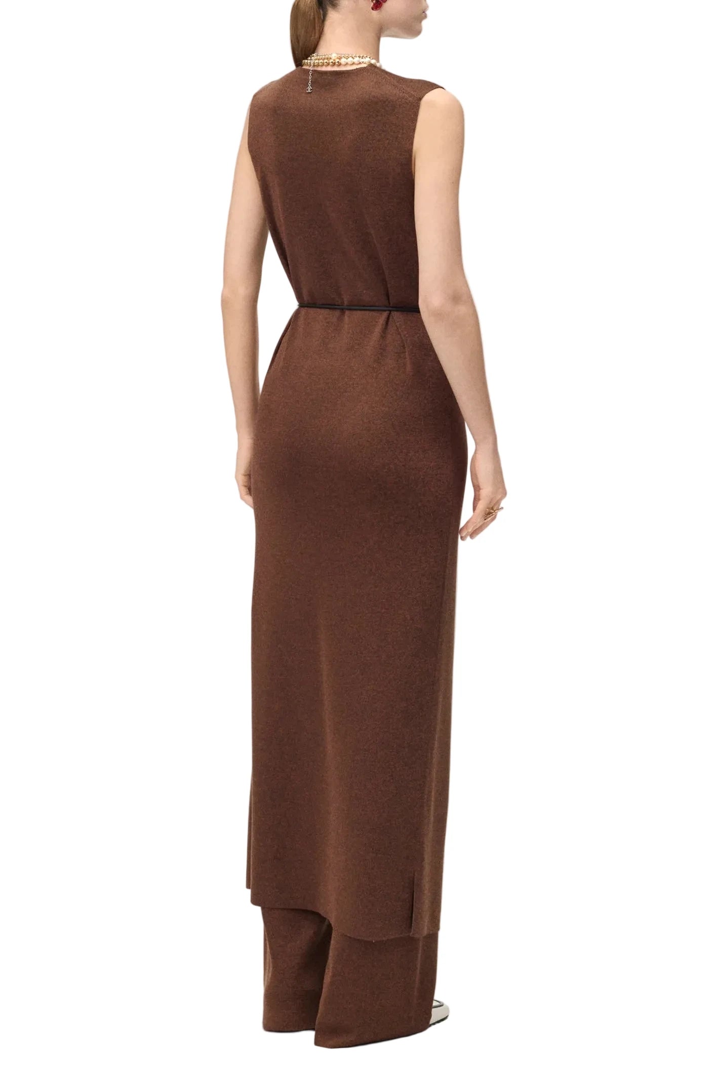 A woman shown from the back wearing a sleeveless brown knit dress with a matching belt and wide-leg trousers, photographed against a plain light background.