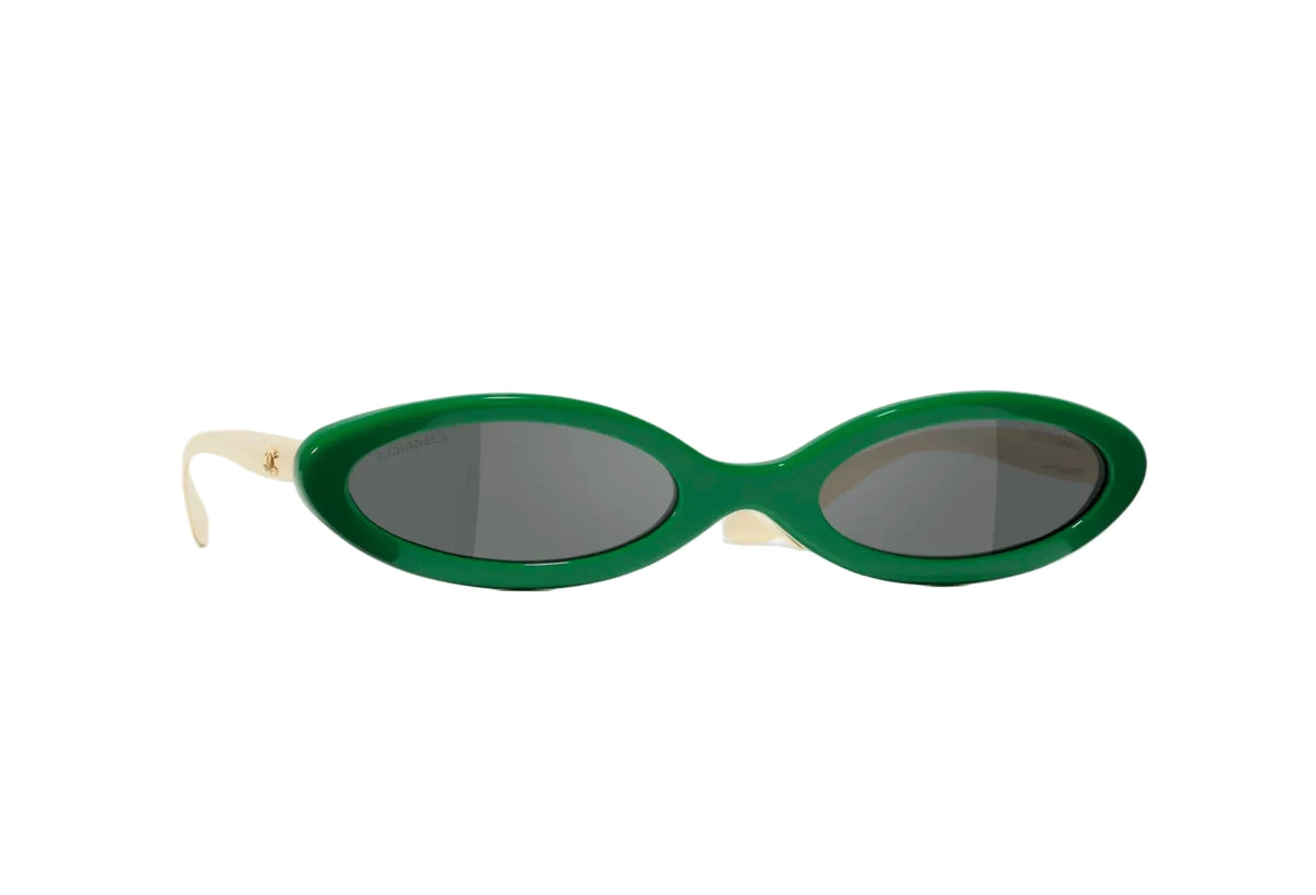 Oval sunglasses with a vibrant green frame and dark gray lenses, featuring cream-colored temples with a small gold logo, set against a plain white background.