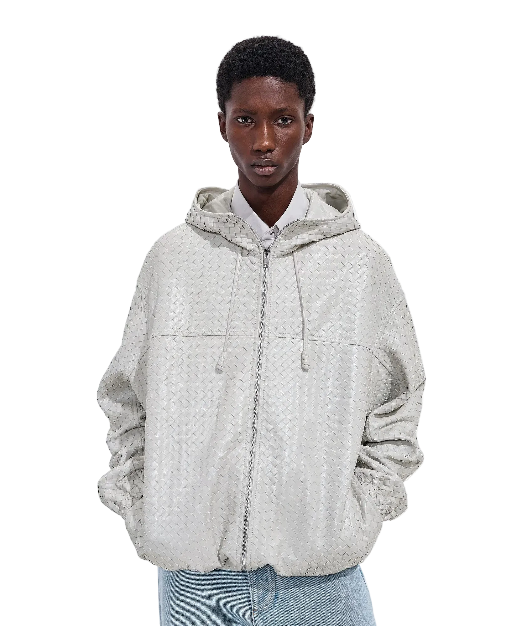 A model wearing a light beige textured zip-up hoodie jacket over a white collared shirt and light blue jeans, shot against a plain white studio background.