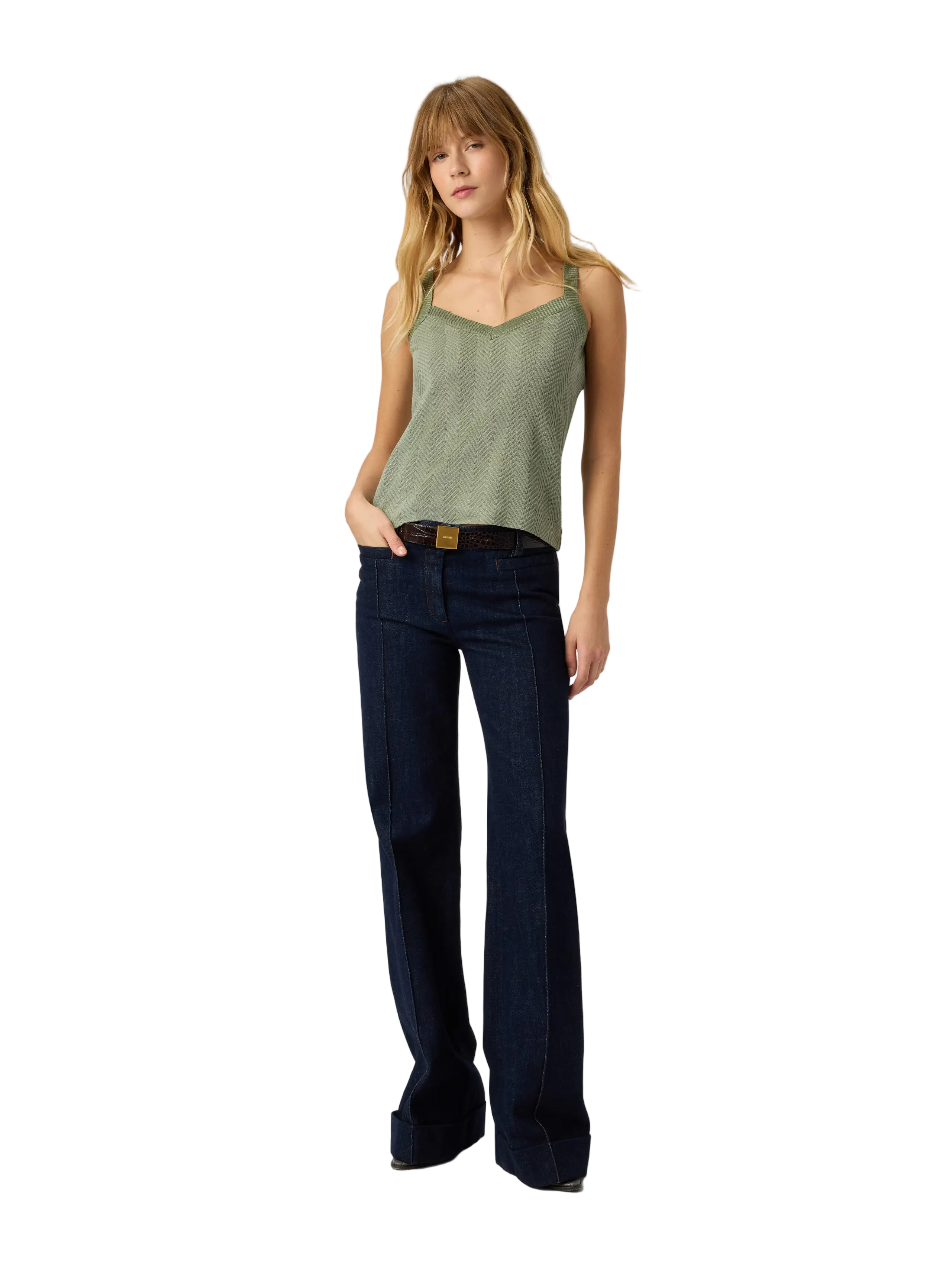 Woman wearing a green tank top and dark blue jeans on a white background