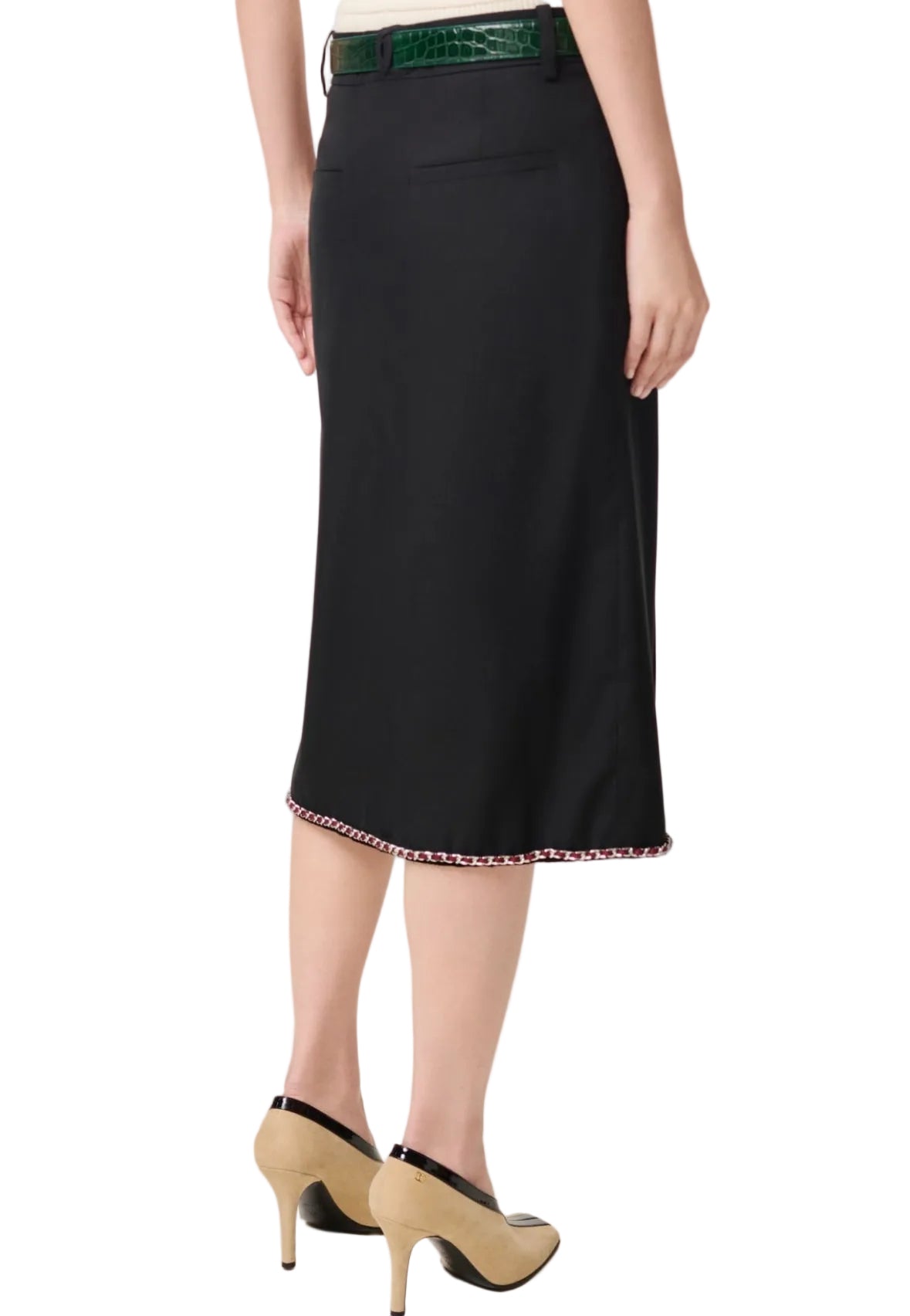 Black skirt with a green belt and beige shoes on a white background