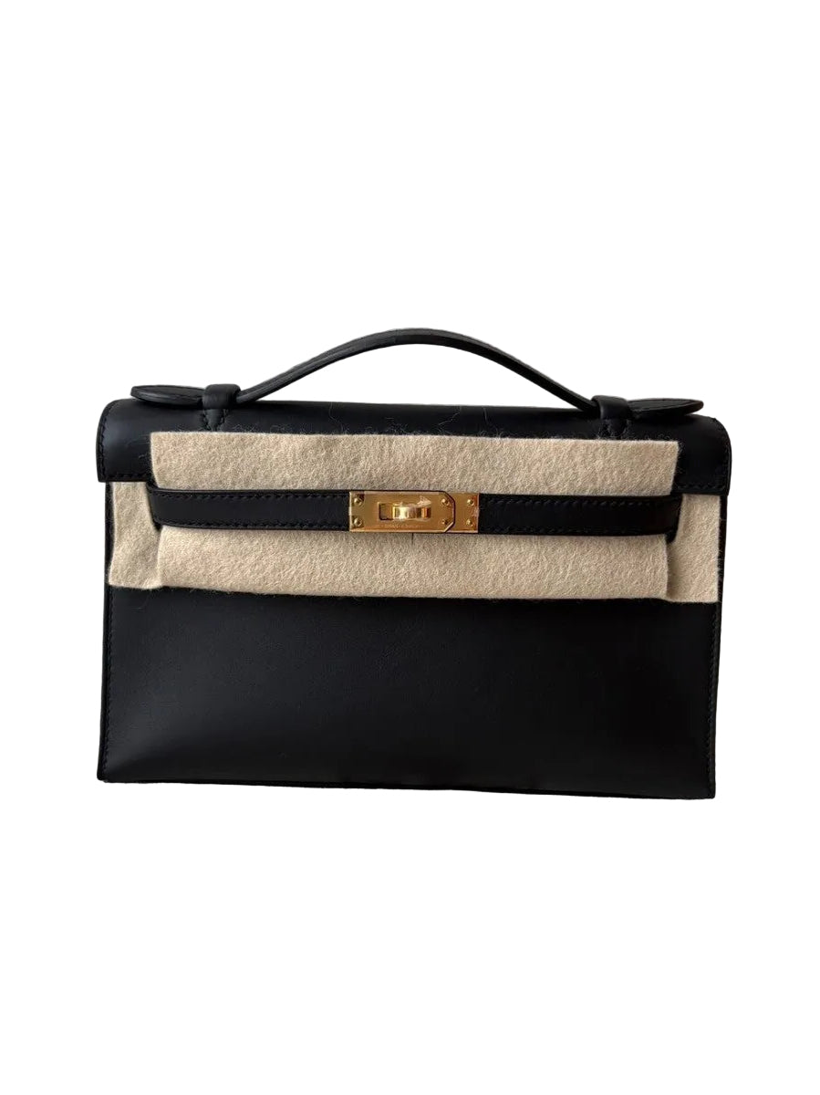 Black and beige handbag with gold clasp on a textured surface