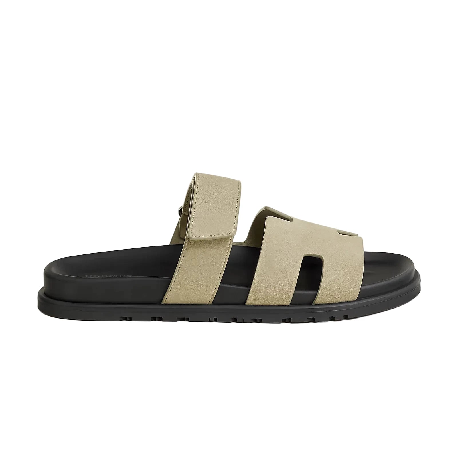 Beige sandal with black sole on a light beige background
