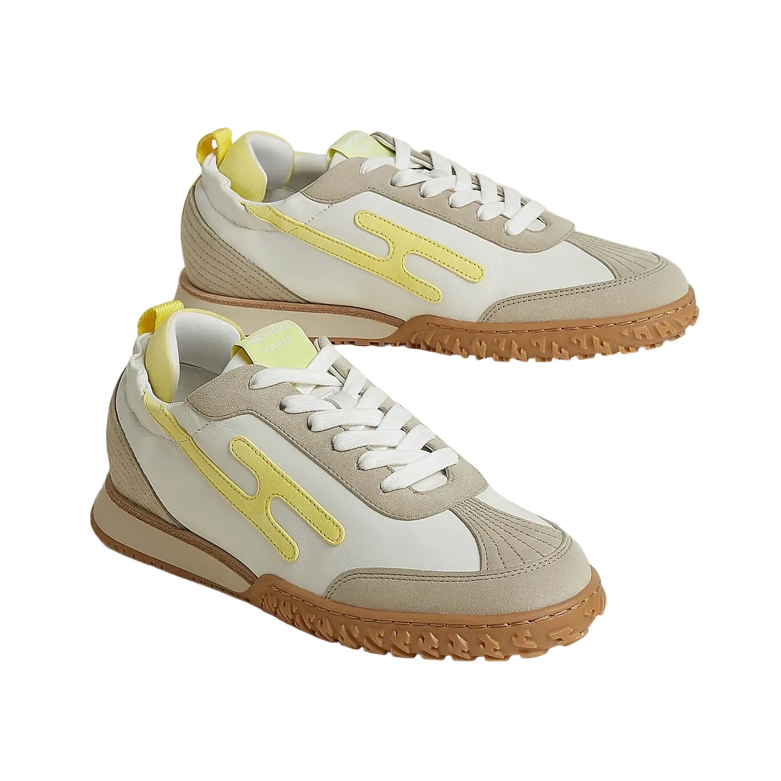 Pair of beige and white sneakers with yellow accents on a light background