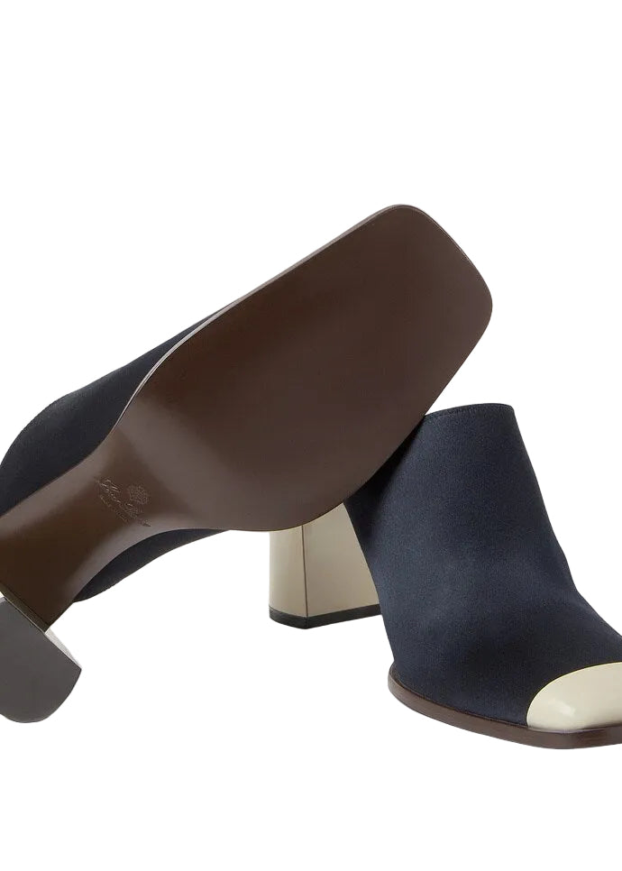 Navy blue suede mules with brown and beige heels on a light gray background