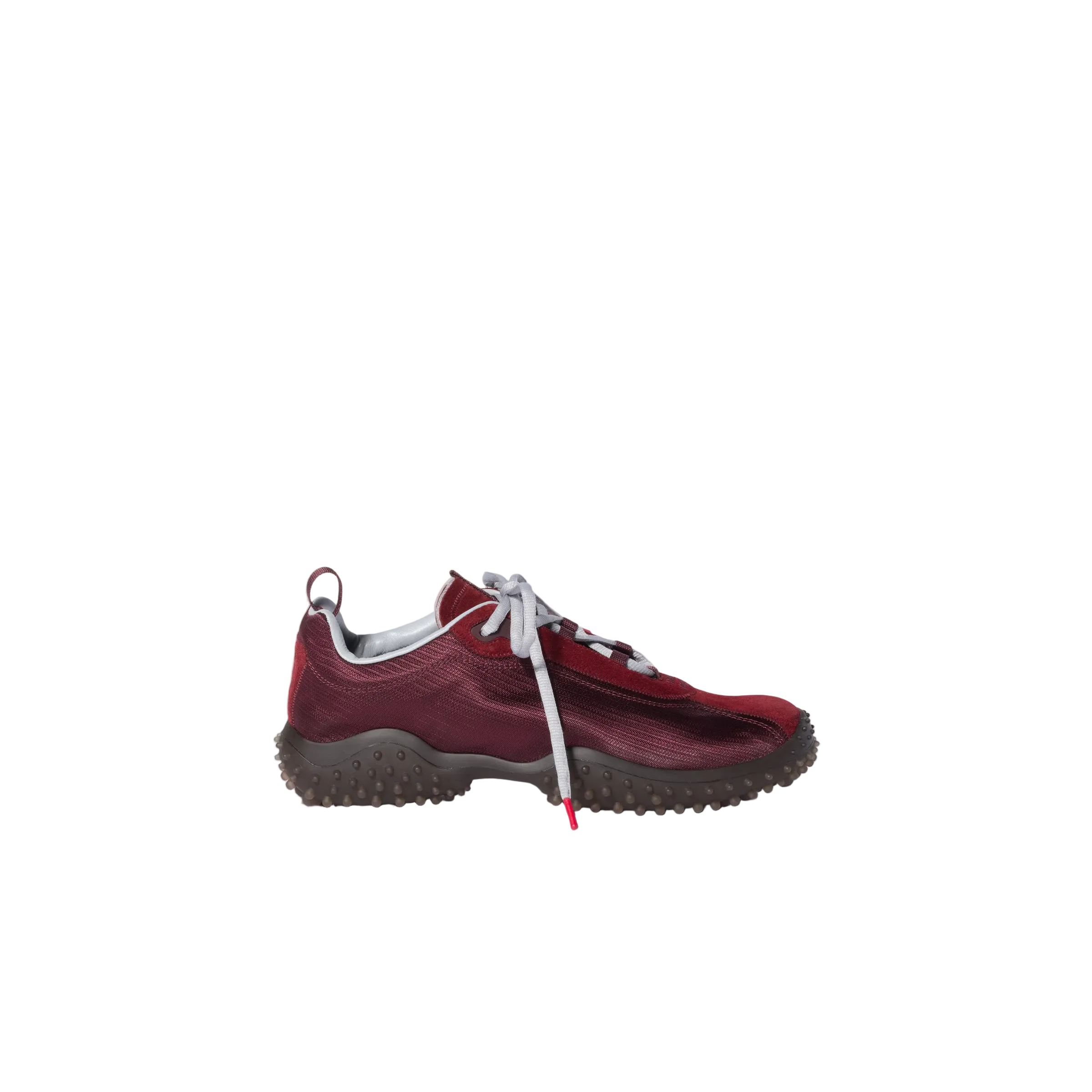 A single low-top athletic shoe in burgundy suede and mesh with white laces and a dark gray textured sole, shown in profile against a light beige background.