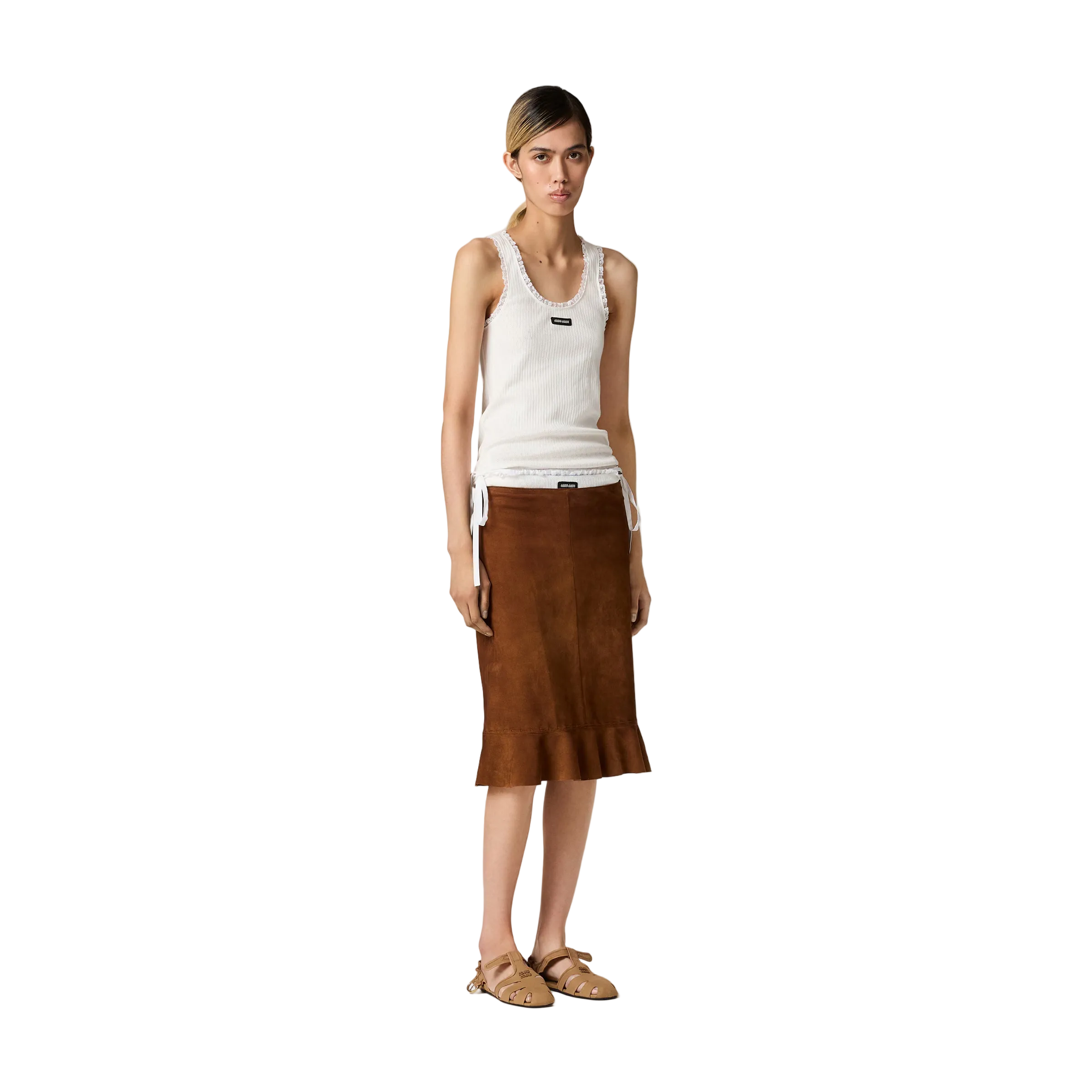 Woman wearing a white tank top and brown skirt on a beige background