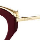 Close-up of Cartier sunglasses showing a deep burgundy acetate frame, a polished gold metal brow piece with a panther head detail, and the Cartier logo engraved on the temple arm against a light off-white background.