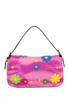 A pink fuzzy shoulder bag with a brown leather strap, decorated with colorful felt flowers and yellow dots, shown against a plain white background.