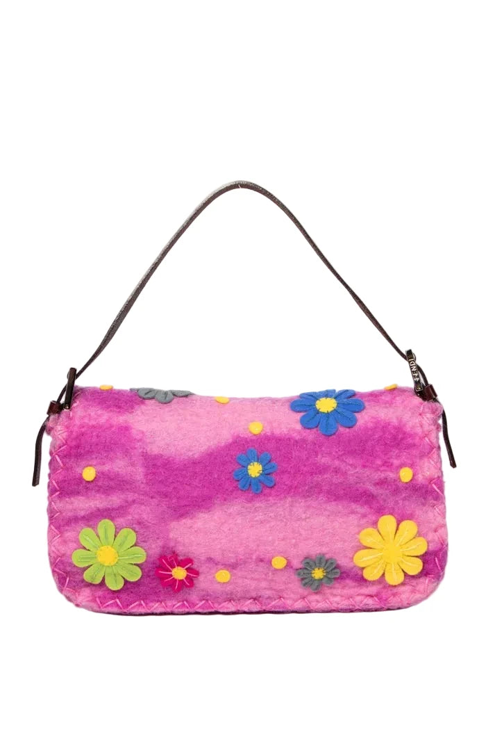 A pink fuzzy shoulder bag with a brown leather strap, decorated with colorful felt flowers and yellow dots, shown against a plain white background.
