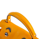Close-up of a bright yellow leather handbag handle with silver-tone hardware against a plain light background.