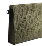 An olive green leather clutch bag featuring an all-over embossed Dior Oblique monogram pattern, shown at a three-quarter angle on a light gray background.