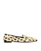 A single flat loafer shoe with a cream-colored hair-on-hide upper featuring black leopard spots, shown in a side profile against a light gray background.