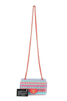 A Chanel shoulder bag with a colorful striped tweed body in pink, blue, and orange, featuring a signature red CC turn-lock closure and a red-and-gold chain strap. A black authenticity card is placed next to the bag on a clean white background.