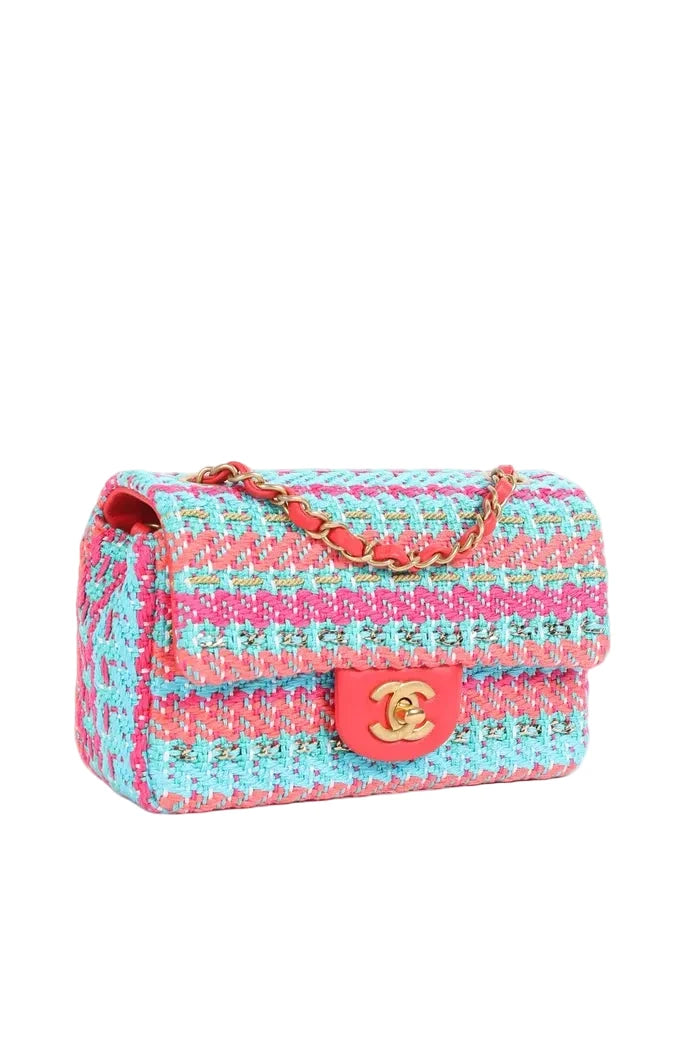 A Chanel tweed flap bag in a pink and turquoise blue woven pattern, featuring a red leather turn-lock closure and a gold-tone chain strap.