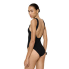 Woman wearing a black swimsuit with a minimal background