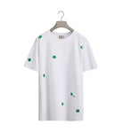 White t-shirt with green clover patterns on a white background