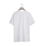 White t-shirt with small yellow patterns on a hanger against a white background
