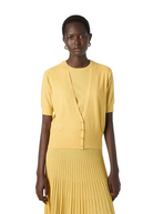 Woman wearing a yellow top and pleated skirt on a white background