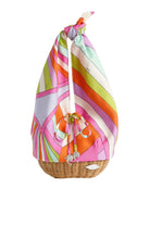 Colorful patterned bag tied over a wicker basket on a white background