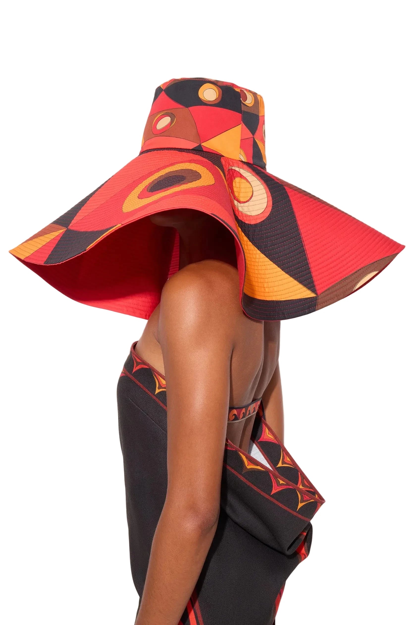 Person wearing a colorful, patterned hat and dress on a light background