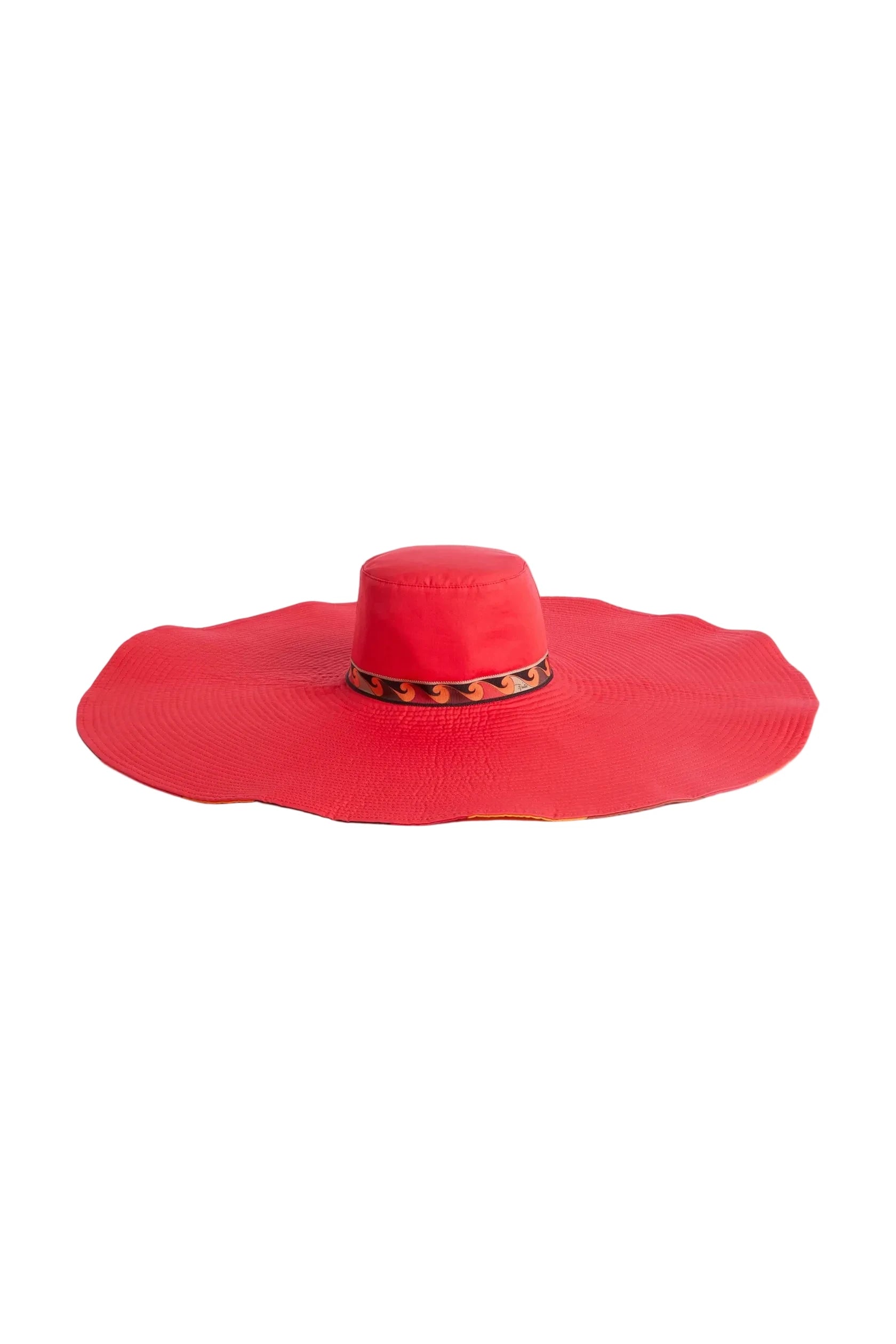 Red sun hat with a wide brim on a light beige background