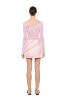 Person wearing a pink and white patterned dress on a plain background