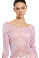 Woman wearing a pink and white patterned dress against a plain background
