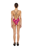 Woman wearing a pink and black swimsuit with criss-cross back design on a white background