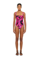 Model wearing a pink and black patterned swimsuit on a white background