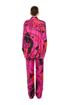 Person wearing a vibrant pink and black patterned suit on a white background