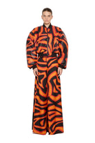 Person wearing a vibrant orange and black patterned outfit on a white background