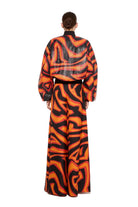 Person wearing a vibrant orange and black patterned outfit on a white background