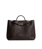 Brown woven handbag with a gold bow on a light gray background