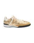 Gold sneaker with white laces on a light gray background