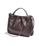 Brown quilted handbag with a chain detail on a white background