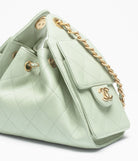 Light green quilted handbag with gold chain and hardware on a white background