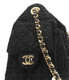 Black textured handbag with gold chain and logo on a white background