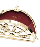 Chanel gold clutch with intricate design on a white background