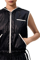 Black sleeveless jacket with white zipper and trim on a neutral background