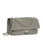 A classic Chanel shoulder bag in gray suede with a gold-tone interlocking CC clasp and a chain strap, shown on a plain white background.