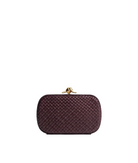 Maroon woven clutch bag with gold clasp on a light gray background