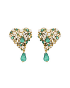 A pair of gold heart-shaped drop earrings embellished with green and white stones, featuring a teardrop-shaped green stone hanging from the center of each earring, set against a plain off-white background.