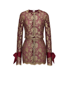 A burgundy lace mini dress with gold floral embroidery, featuring long sleeves with matching burgundy ribbon bows at the cuffs, a round neckline, and a lace-up front closure, shown against a plain light background.