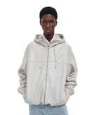 A model wearing a light beige textured zip-up hoodie jacket over a white collared shirt and light blue jeans, shot against a plain white studio background.