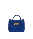 A vibrant blue woven leather handbag with a top handle and a decorative gold metal bow on the front, set against a plain white background.