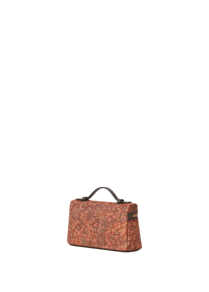 A small structured handbag with a warm rust-orange and brown paisley pattern, featuring dark brown leather trim and a top handle, set against a solid off-white background.