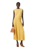 Woman wearing a yellow sleeveless top and pleated skirt holding a brown handbag on a white background